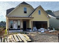A partly constructed yellow home with a two-car garage and a covered porch, still undergoing construction at 1243 Lakeside Overlook, Canton, GA 30114