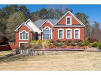 Charming two-story red brick home with manicured front yard, colorful flowers, and inviting entrance at 725 First Cotton Dr, Powder Springs, GA 30127