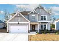 Charming two-story home with a two-car garage, landscaped yard, and classic architectural details at 7545 Rambling Vale, Cumming, GA 30028