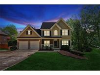 Charming two-story home featuring a manicured lawn, brick accents, a two-car garage, and traditional architectural details at 5815 P.W.A. Dr, Cumming, GA 30041
