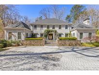 Elegant home featuring a stately facade, stone accents, arched entry, and circular driveway at 4578 Polo Se Ln, Atlanta, GA 30339