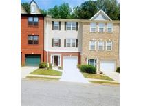 Three-story brick and tan townhomes with garages in a residential community offer a comfortable living space at 523 Lantern Wood Dr, Scottdale, GA 30079