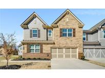 Charming two-story home featuring a brick and stone facade, complemented by shutters and a two-car garage at 2910 Bishopstone Way, Cumming, GA 30040