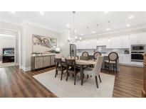 Bright dining room boasts modern chandelier, table with seating for six, and views into the kitchen at 1929 Finnish Ln, Kennesaw, GA 30152