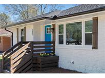 Charming white brick home features a bright blue front door and wooden porch at 1882 Rosewood Rd, Decatur, GA 30032