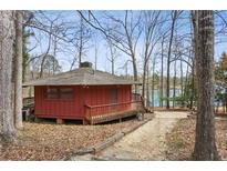 Charming lake house features a stone chimney, rustic wood siding, and a wraparound porch nestled among mature trees at 6535 Smith Cove Way, Cumming, GA 30041