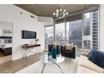 Bright living room with city views, modern furnishings, and hardwood flooring at 855 Peachtree Ne St # 1508, Atlanta, GA 30308