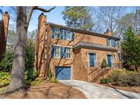 Charming brick townhome showcasing a well-manicured lawn, blue shutters, and convenient garage at 1143 Morningside Ne Pl, Atlanta, GA 30306