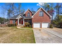Beautiful two-story brick home with a well-manicured lawn, two-car garage, and a welcoming red front door at 525 James Lee Dr, Suwanee, GA 30024