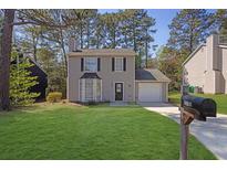 Charming two-story home featuring a landscaped yard, attached garage and large front windows at 2143 Victoria Pl, Lithonia, GA 30058