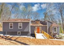 Charming gray home with a wooden walkway and a welcoming orange front door, perfect for any homeowner at 980 Pine Grove Pointe Dr, Roswell, GA 30075