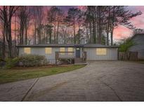 Charming single-story home with a gray exterior, inviting front porch, and a long driveway surrounded by mature trees at 4953 Apple Valley Rd, Douglasville, GA 30135