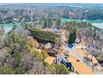 Expansive aerial view of a lakefront home with mature trees and lush landscaping around the property at 3795 Duckcove Way, Cumming, GA 30041
