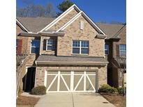 Charming brick townhome with a two-car garage and well-maintained landscaping in a desirable neighborhood at 4440 Cedar Bridge Walk, Suwanee, GA 30024