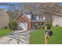 Charming two-story home with manicured lawn, brick accents and a lovely, blooming tree at 7176 Ravenwood Ln, Lithonia, GA 30038