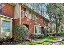 Charming red brick townhome featuring a bay window and well-manicured front yard at 1384 Sheffield Glen Ne Way, Atlanta, GA 30329