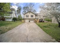 Split level home with neutral siding, attached two car garage, and long driveway at 1517 Cherry Hill Sw Rd, Conyers, GA 30094