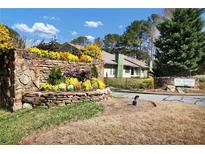 Inviting community entrance with stone wall, colorful flowers and view of the buildings at The Springs at 1281 Branch Dr, Tucker, GA 30084