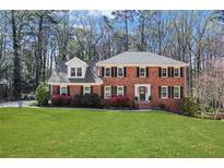 Charming two-story brick home with a manicured lawn, black shutters, and blossoming flower beds at 1135 Parkview Sw Way, Lilburn, GA 30047