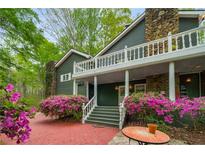 Charming home entrance with brick path, stone chimney and stairs leading to a covered porch with vibrant azaleas at 2977 Glover Dr, Cumming, GA 30040