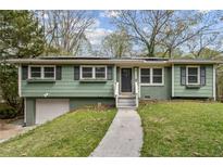 Charming home with green exterior, black shutters, lovely landscaping and a welcoming front porch at 2610 Crestdale Se Cir, Atlanta, GA 30316
