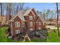 Inviting brick home with manicured lawn and landscaping in a beautiful wooded setting at 5388 Frazer Rd, Buford, GA 30518