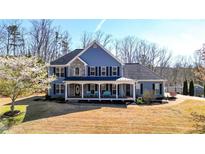 Charming two-story home with a rocking chair front porch, a manicured lawn, and mature trees at 114 Hardwood Ln, Canton, GA 30115