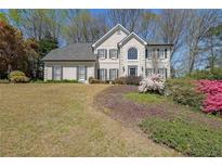 Charming two-story home with black shutters and beautifully landscaped front yard and blooming azaleas at 1201 Lake Washington Dr, Lawrenceville, GA 30043