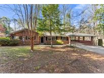 Charming brick home featuring a carport and a spacious front yard with mature trees at 2928 Henderson Rd, Tucker, GA 30084