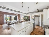 Modern kitchen with stainless steel appliances, white cabinets, and island that opens to the living room with brick wall at 791 Wylie Se St, Atlanta, GA 30316