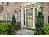 Charming brick home entrance with decorative glass door, sidelights, arched windows, and manicured landscaping at 6317 Southland Forest Dr, Stone Mountain, GA 30087