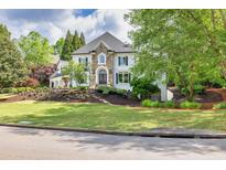 Elegant home with stone accents, manicured lawn, and lush landscaping offers great curb appeal at 2335 Flat Stone Dr, Cumming, GA 30041