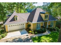 Charming home featuring a two-car garage, manicured landscaping, and a unique turret-style architectural detail at 1187 Plantation Dr, Villa Rica, GA 30180
