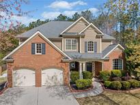 Beautiful brick and tan home featuring a two-car garage, well-manicured landscaping, and a charming covered front porch at 548 Lawton Bridge Sw Rd, Smyrna, GA 30082