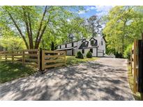 Charming home featuring a classic black and white exterior, a wooden fence and a private driveway at 110 Myers Dr, Alpharetta, GA 30009