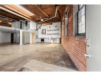Bright open living area with exposed brick, loft, and modern kitchen details under a wood ceiling at 644 Wells Sw St # 8, Atlanta, GA 30310