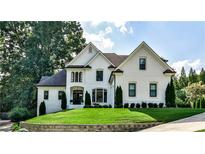Elegant, two-story white brick home with manicured lawn and mature trees, exuding curb appeal and classic charm at 237 Webney Se Dr, Marietta, GA 30068