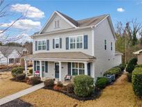 Charming two-story home featuring blue shutters, a covered front porch, and manicured landscaping at 300 South Village Sq, Canton, GA 30115