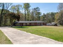 Sprawling single story home featuring a brick facade, mature trees and a long driveway at 3042 Peek Nw Rd, Atlanta, GA 30318