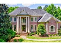Grand brick home featuring stately columns, arched windows, mature trees, and lush landscaping at 2698 Bonar Hall Path, Duluth, GA 30097