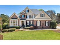 Beautiful brick home featuring manicured lawn, mature trees, and architectural design elements at 305 Inman Pl, Roswell, GA 30075