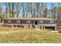 Ranch-style home featuring a brick facade, mature landscaping, and an attached garage in a suburban setting at 3819 Dora Se Dr, Smyrna, GA 30082