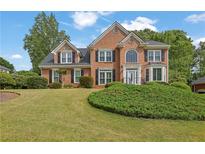 Beautiful brick home with well-manicured lawn, mature trees, and classic architectural details at 269 Hidden Wood Ct, Lawrenceville, GA 30043
