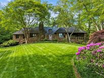 Charming stone cottage-style home with a lush green lawn, mature trees, and blooming flowers at 1050 E Club Ne Ln, Atlanta, GA 30319