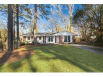Charming brick home featuring manicured front lawn and mature trees on a sunny day at 2299 Brenda Se Dr, Smyrna, GA 30080