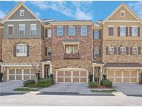 Charming townhome exterior with brick and stone accents, multi-car garage, and neat landscaping at 971 Thibideau Ct, Sandy Springs, GA 30328