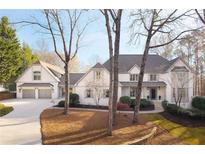 Charming two-story traditional home featuring a manicured lawn, beautiful landscaping, and a three-car garage at 8705 River Trce, Roswell, GA 30076