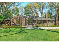 Charming home boasts a manicured lawn, lush landscaping, and a striking modern design with large windows at 1718 Barnesdale Ne Way, Atlanta, GA 30309