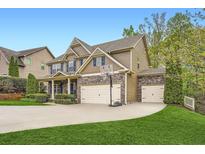 Beautiful two-story home featuring a three car garage, stone accents, and manicured lawn at 317 Water Oak Ln, Canton, GA 30114