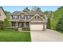 Inviting two-story home with a well-manicured lawn, stone accents, and a basketball hoop over the garage at 317 Water Oak Ln, Canton, GA 30114